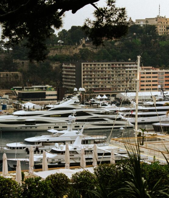 monaco-gp-harbour-luxury-yachts Luxury mega yachts docked in Monaco's Port Hercules, framed by Mediterranean greenery and iconic Monte Carlo architecture during the Monaco GP Fashion 2026 showcase.